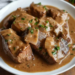 Tender Crockpot Cubed Steak with creamy gravy on a white plate garnished with fresh parsley