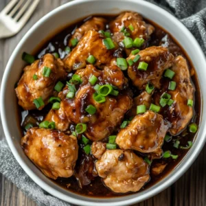 Bowl of Crockpot Chicken Adobo garnished with green onions, showcasing tender chicken in rich sauce