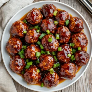 Crockpot Kung Pao Meatballs on a white plate garnished with green onions in a warm, inviting setting