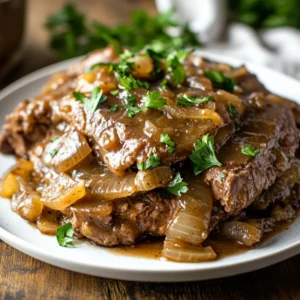 Slow Cooker French Onion Swiss Steak on a white plate topped with parsley, showcasing rich sauce and tender meat